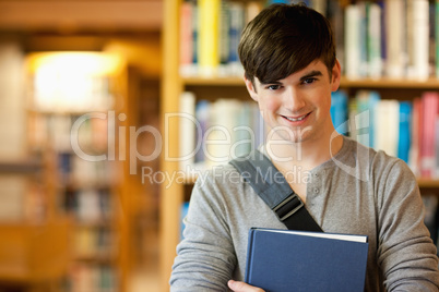 Smiling young student holding a book