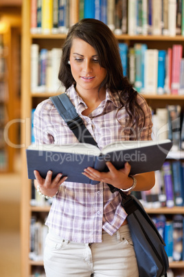 Portrait of a cute young student reading a book