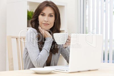 Woman Using Laptop Computer At Home Drinking Tea or Coffee