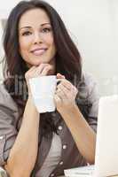 Woman Using Laptop Computer At Home Drinking Tea or Coffee