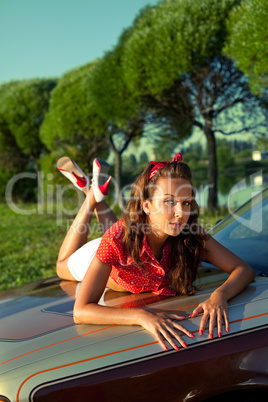 Young woman lay on retro car in summer sunset