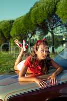 Young woman lay on retro car in summer sunset