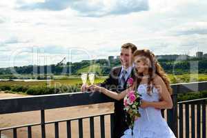 Wedding couple in sunny summer day stand on bridge