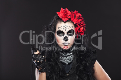 Serious woman in day of the dead mask with gun