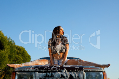 sexy woman washing a car at sunset