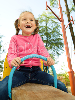 Cute little girl is swinging on see-saw