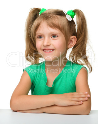 Happy little girl is sitting at the table