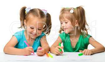 Two little girls draw with markers