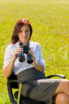 Businesswoman sit in sunny meadow seek binocular