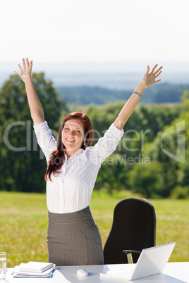 Businesswoman in sunny nature office hands up