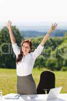Businesswoman in sunny nature office hands up