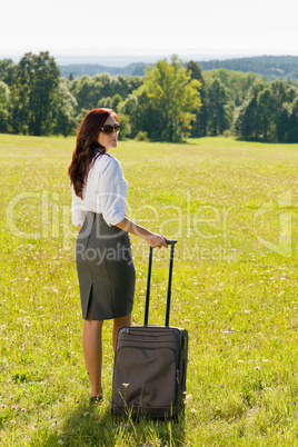 Businesswoman sunny meadow leaving with luggage