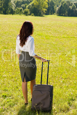 Businesswoman sunny meadow leaving with luggage