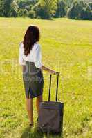 Businesswoman sunny meadow leaving with luggage