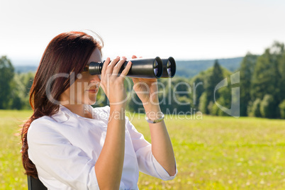 Businesswoman sit in sunny meadow seek binocular