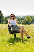 Businesswoman sit in sunny meadow seek binocular