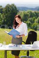 Businesswoman in sunny nature office look folder