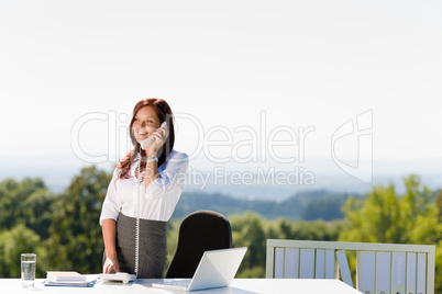 Businesswoman in sunny nature office calling