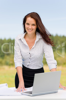 Businesswoman in sunny nature smiling with laptop