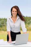 Businesswoman in sunny nature smiling with laptop