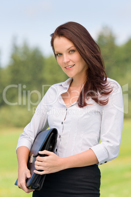 Businesswoman in sunny nature smiling briefcase
