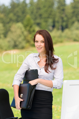 Businesswoman in sunny nature smiling briefcase