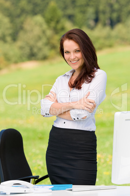 Businesswoman in sunny nature smiling crossed arms