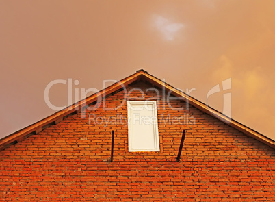 Fragment of brick house in the background reddish thunderclouds.