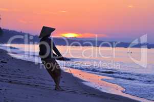 Silhouette of a fisherman on beach at sunrise