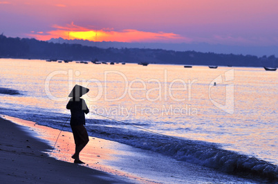Silhouette of a fisherman on beach at sunrise