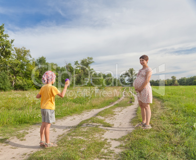 Small boy making soap bubbles with his regnant mother