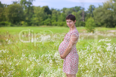 Pregnant woman on chamomile meadow