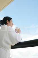 woman with morning coffee looking through balcony