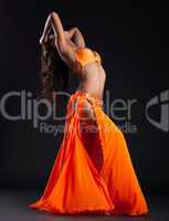 Expressive woman posing in orange arabic costume