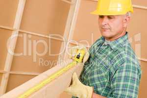 Handyman mature carpenter measure wooden beam