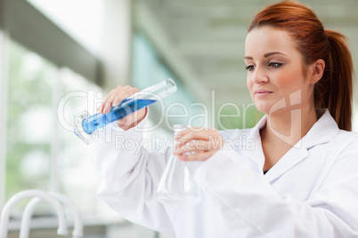 Scientist pouring liquid in an Erlenmeyer flask