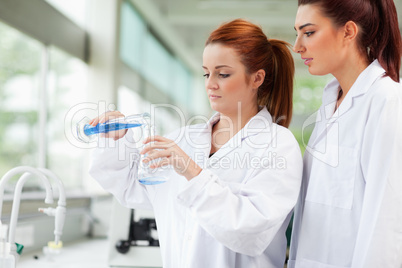 Cute scientists pouring liquid in an Erlenmeyer flask