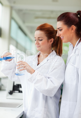 Portrait of scientists pouring liquid in an Erlenmeyer flask