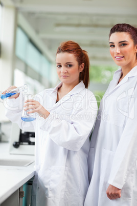 Portrait of scientists pouring blue liquid in an Erlenmeyer flas