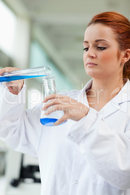 Portrait of a scientist pouring blue liquid in an Erlenmeyer fla