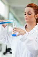 Portrait of a scientist pouring blue liquid in an Erlenmeyer fla