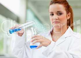 Cute scientist pouring blue liquid in an Erlenmeyer flask