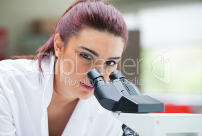 Close up of a young scientist posing with a microscope