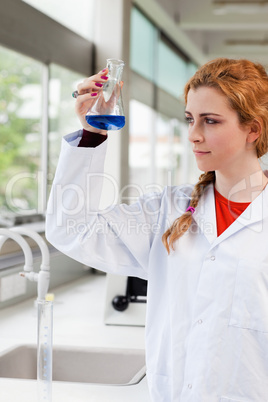 Portrait of a chemist looking at a blue liquid