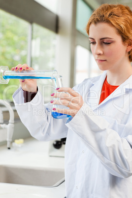 Portrait of a red-haired scientist pouring liquid
