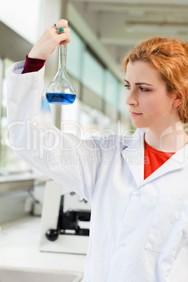 Portrait of a cute scientist holding a blue liquid