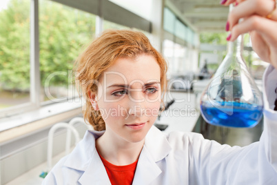 Cute science student holding a blue liquid