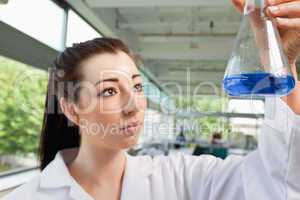 Brunette looking at a blue liquide