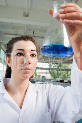 Portrait of a brunette looking at a blue liquid
