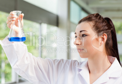 Cute science student looking at a blue liquid